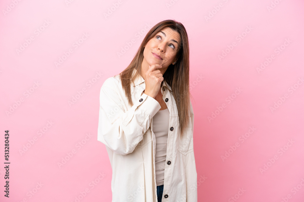 Middle age caucasian woman isolated on pink background and looking up Middle age caucasian woman isolated on pink background and looking up