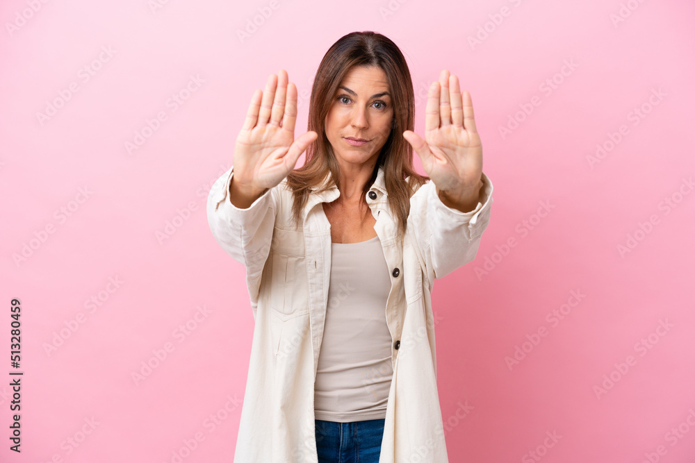 Middle age caucasian woman isolated on pink background making stop gesture and disappointed Middle age caucasian woman isolated on pink background making stop gesture and disappointed