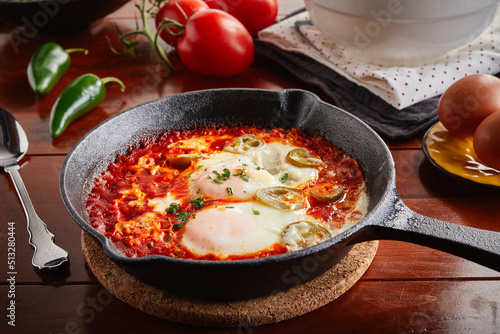 Shakshuka served in a fry pan isolated on wooden background side view of arabic food photo