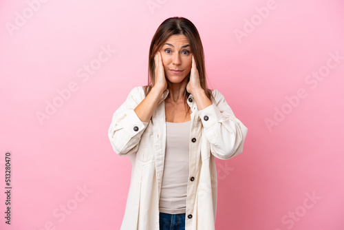 Middle age caucasian woman isolated on pink background frustrated and covering ears © luismolinero