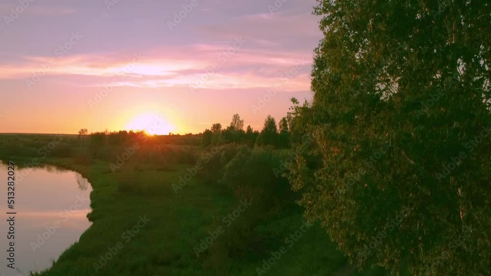 An orange-pink sunset in a birch grove on the river bank, shot by a drone. An orange-pink sunset in a birch grove on the river bank, shot by a drone.