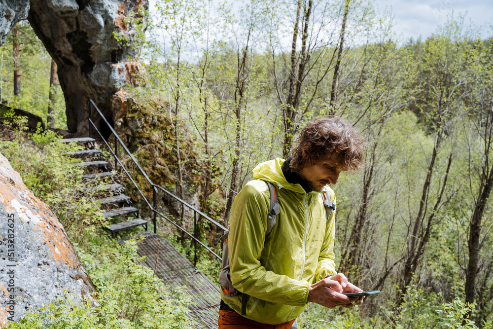 A tourist got lost in the forest, call an emergency help service by phone, sos a signal on a smartphone, type text with his fingers on the screen of the gadget. A tourist got lost in the forest, call an emergency help service by phone, sos a signal on a smartphone, type text with his fingers on the screen of the gadget.