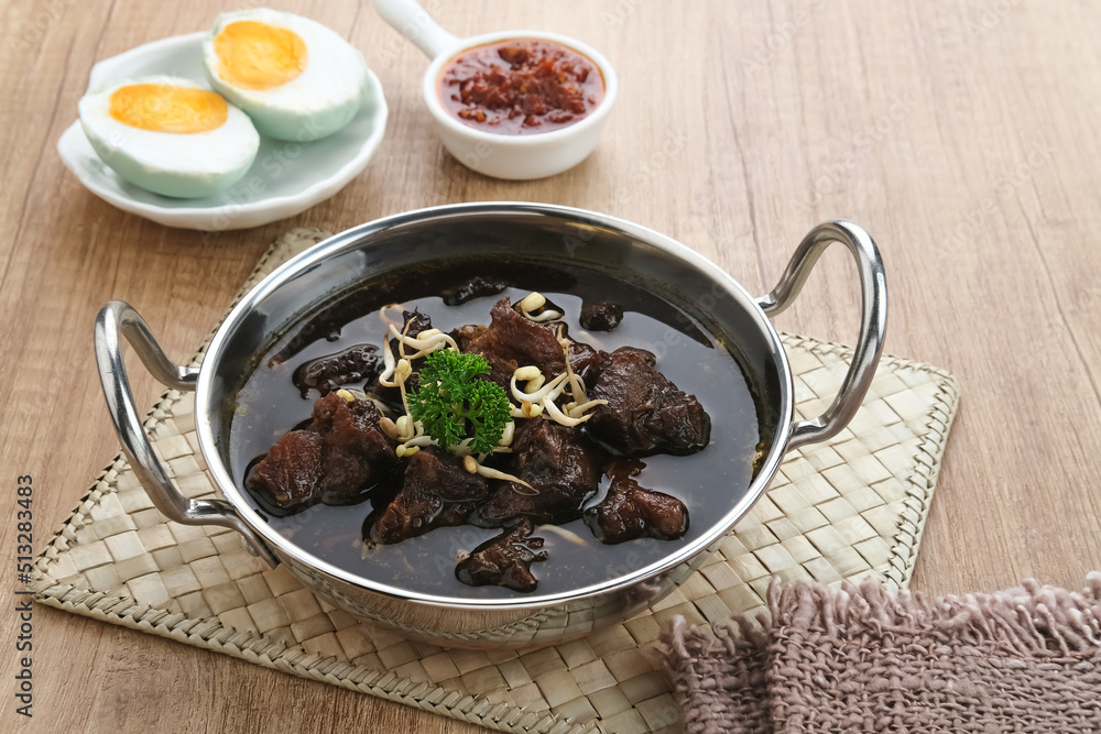 Rawon, Indonesian Traditional beef black soup. Served on a bowl with mung bean sprouts, chilli paste and salted egg
Rawon, Indonesian Traditional beef black soup. Served on a bowl with mung bean sprouts, chilli paste and salted egg