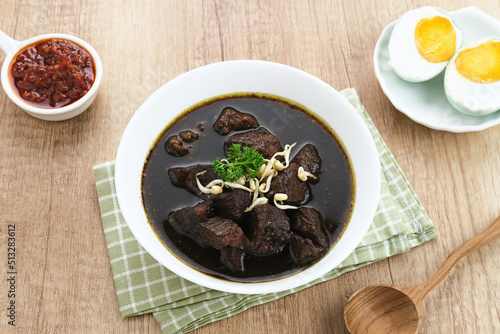 Rawon, Indonesian Traditional beef black soup. Served on a bowl with mung bean sprouts, chilli paste and salted egg
 photo