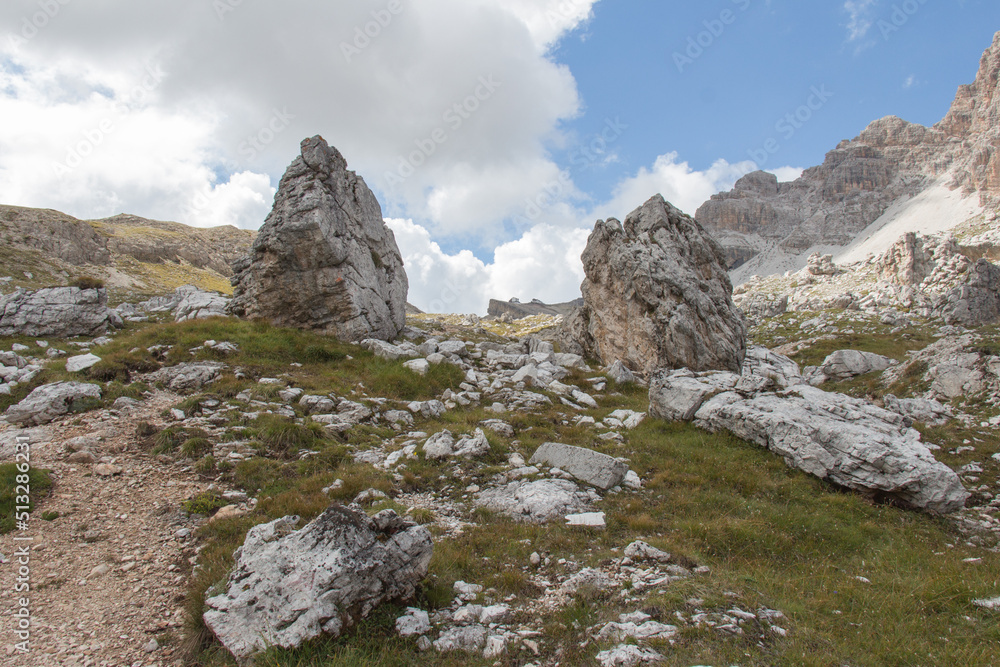 Mountain landscape in a sunny day. Two rock outcrop in a valley surrounded by mountain massif, Dolomites, Italian Alps.