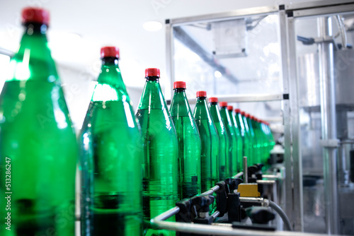 Plastic bottles on conveyor belt being filled with drinking water.