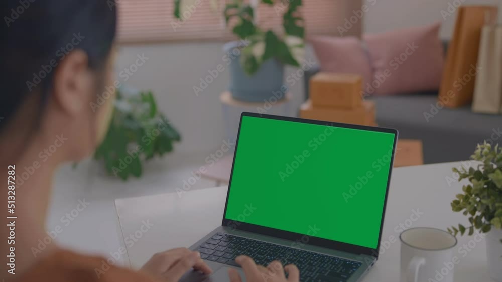 Over the shoulder shot of a business woman working in office interior on pc on desk, looking at green screen. Office person using laptop computer with laptop green screen. Over the shoulder shot of a business woman working in office interior on pc on desk, looking at green screen. Office person using laptop computer with laptop green screen.