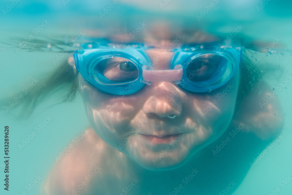 Little baby in swimming goggles, girl swim underwater in paddling pool ...