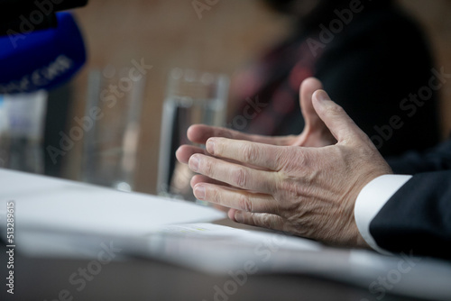 Close Up Executive Lawyer or JUDGE HAND Striking the GAVEL on Sounding Block in LAW OFFICE, JUSTICE and LAW Concept Background, Businessmen in Suits sitting on the table Next to a ็ammer.