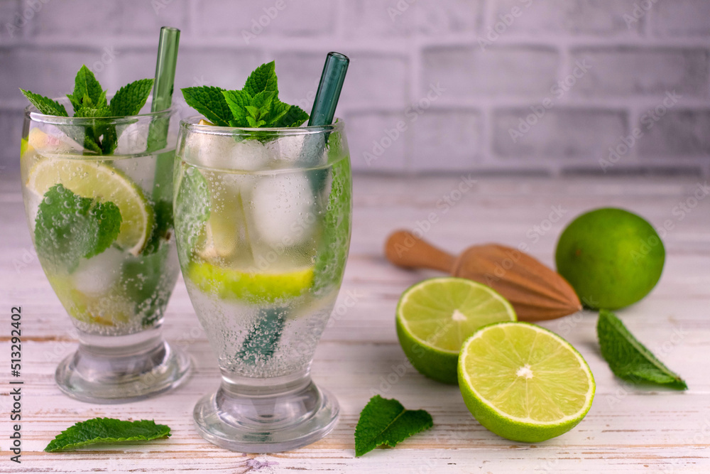 Fototapeta premium Two glasses of mojito on a white wooden table. Refreshing summer drink.