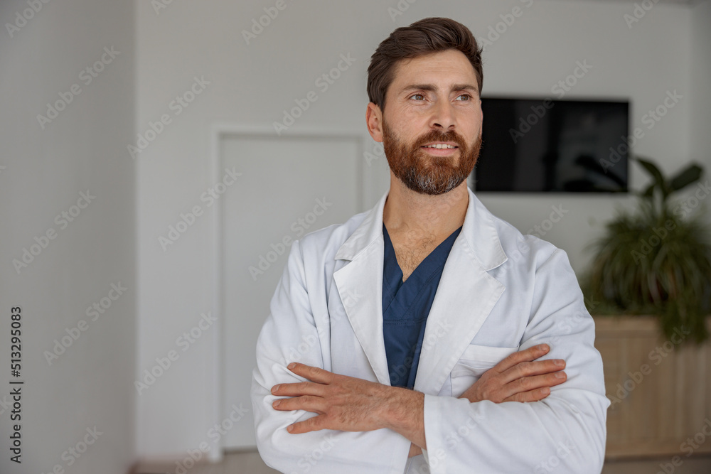 Portrait of handsome doctor in uniform standing in medicine clinic hall and looking away Portrait of handsome doctor in uniform standing in medicine clinic hall and looking away