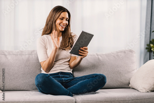 A happy woman has a video call on tablet from home.