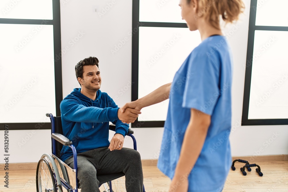 Young disabled man and physiotherapist smiling happy shaking hands at the clinic. Young disabled man and physiotherapist smiling happy shaking hands at the clinic.
