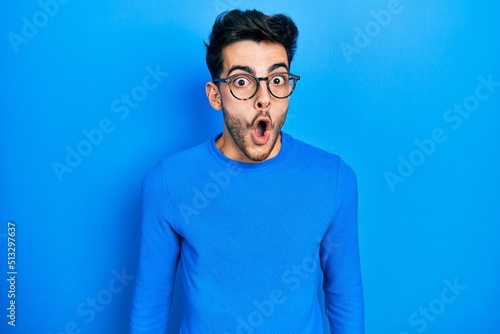 Young hispanic man wearing casual clothes and glasses afraid and shocked with surprise expression, fear and excited face.