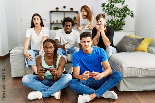 Group of young friends smiling happy playing video game at home.