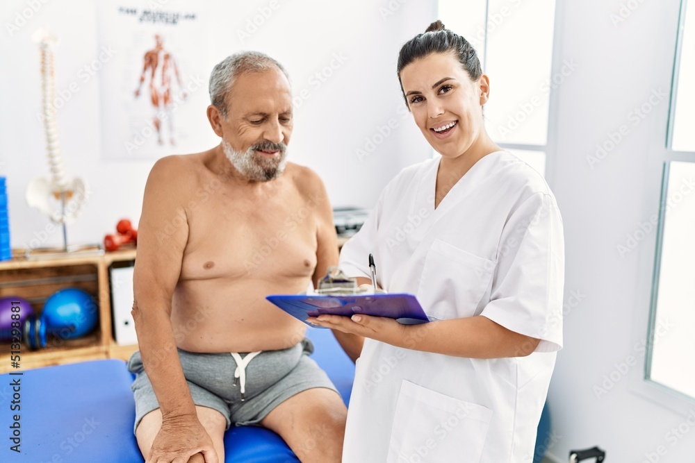 Physiotherapist and patient smiling confident having rehab session at clinic Physiotherapist and patient smiling confident having rehab session at clinic