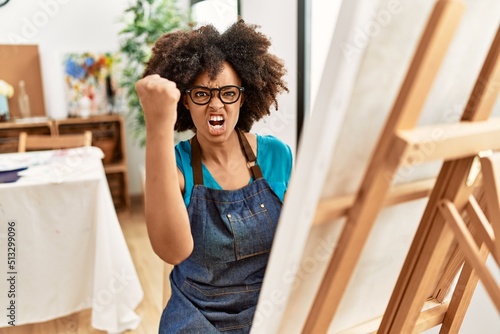 Beautiful african american woman with afro hair painting canvas at art studio annoyed and frustrated shouting with anger, yelling crazy with anger and hand raised