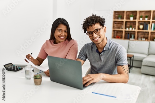 Young latin couple working using laptop sitting on the table at home. © Krakenimages.com