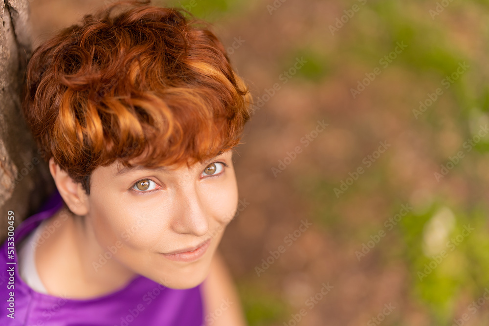 Glad androgynous woman relaxing near a tree