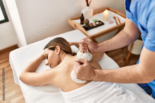 Young woman reciving herbal pouches thai massage at beauty center.