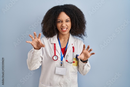 Young african american woman wearing doctor uniform and stethoscope smiling funny doing claw gesture as cat  aggressive and sexy expression