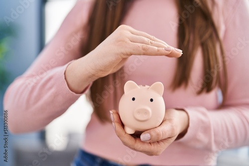 Young woman holding piggy bank at home