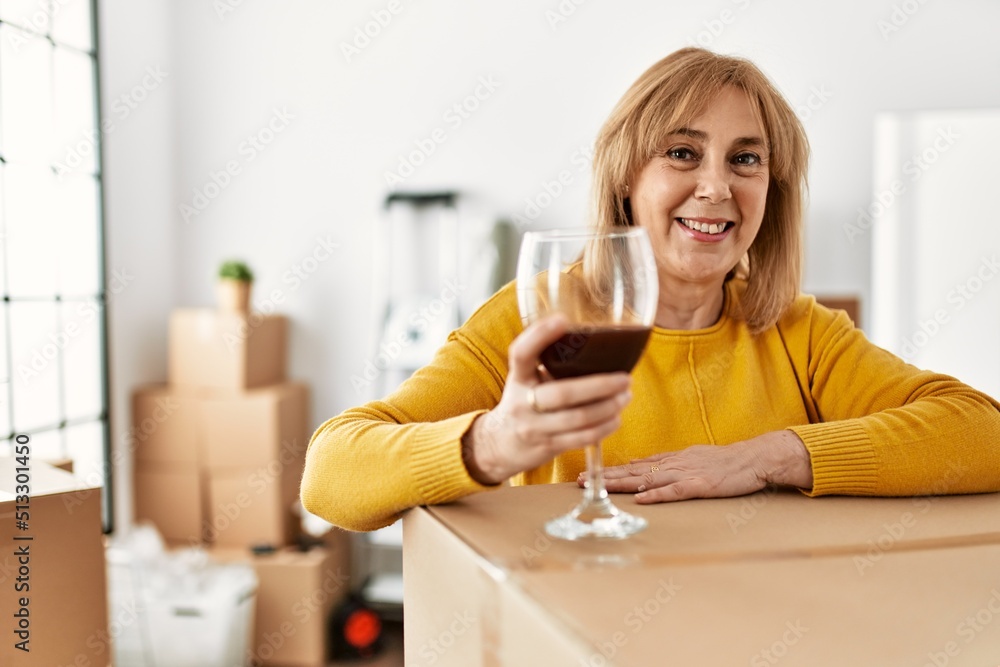Middle age blonde woman smiling happy drinking red wine at new home. Middle age blonde woman smiling happy drinking red wine at new home.