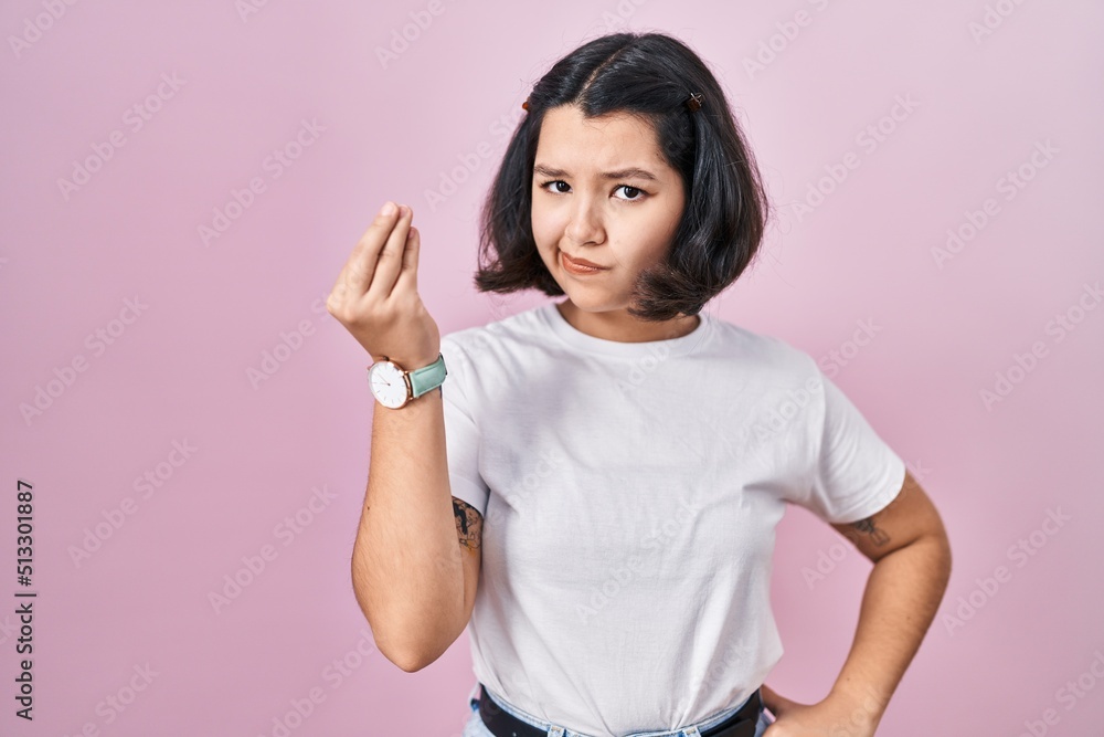 Young hispanic woman wearing casual white t shirt over pink background doing italian gesture with hand and fingers confident expression Young hispanic woman wearing casual white t shirt over pink background doing italian gesture with hand and fingers confident expression