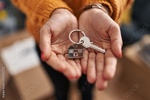 Young latin woman holding key of new house at new home photo