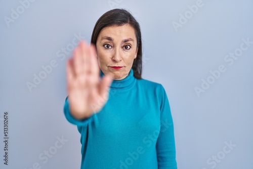 Wallpaper Mural Middle age hispanic woman standing over isolated background doing stop sing with palm of the hand. warning expression with negative and serious gesture on the face. Torontodigital.ca