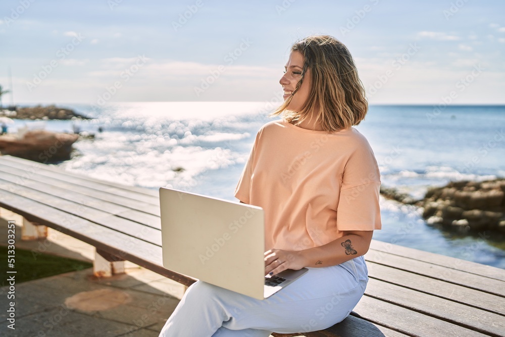 Young hispanic woman smiling confident using laptop at seaside