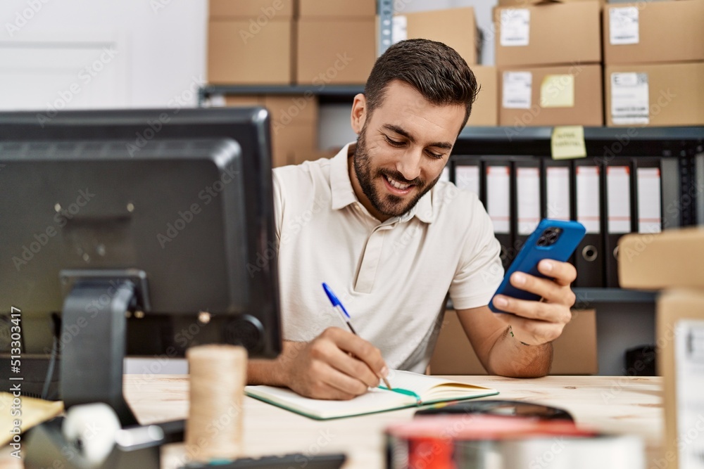Young hispanic man smiling confident using smartphone at storehouse