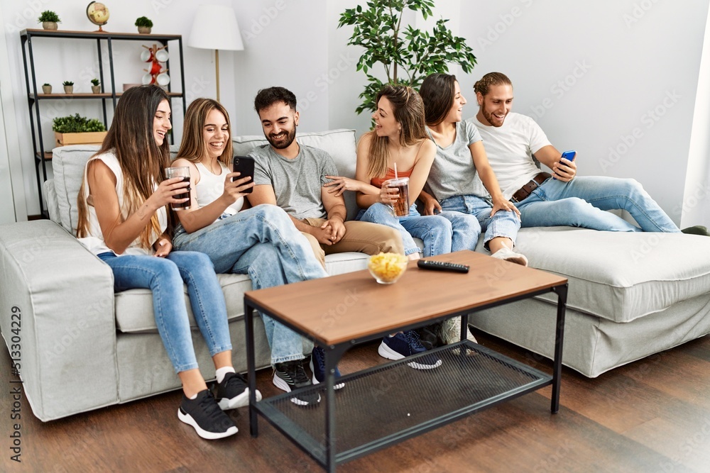 Group of young friends smiling happy and using smartphone sitting on the sofa at home. Group of young friends smiling happy and using smartphone sitting on the sofa at home.