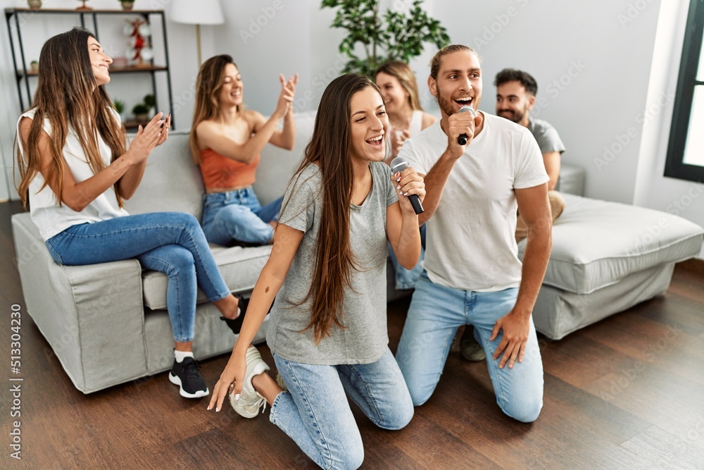 Group of young friends having party singing song using microphone at home. Group of young friends having party singing song using microphone at home.