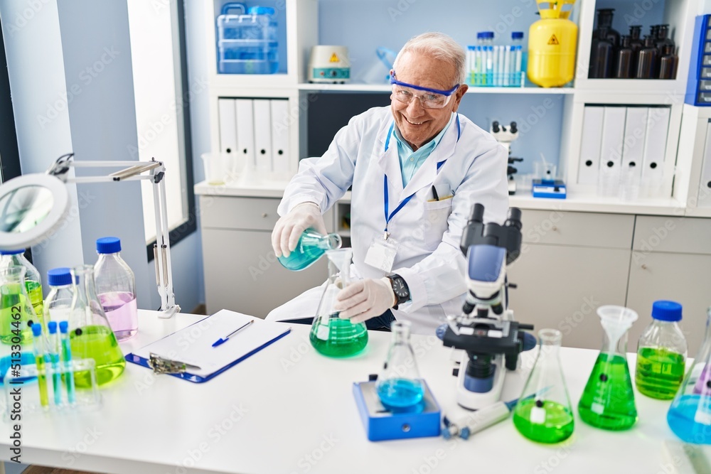 Senior man wearing scientist uniform pouring liquid at laboratory Senior man wearing scientist uniform pouring liquid at laboratory