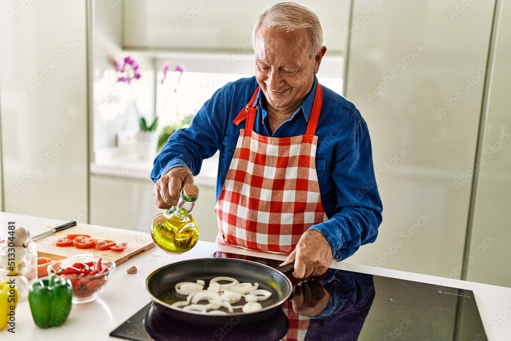Senior man smiling confident pouring oil on frying pan at kitchen Senior man smiling confident pouring oil on frying pan at kitchen