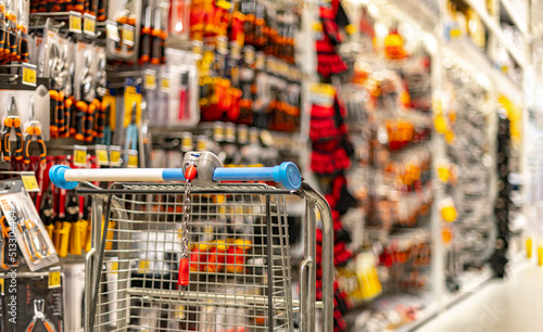 A shopping cart by a store shelf in a hardware store