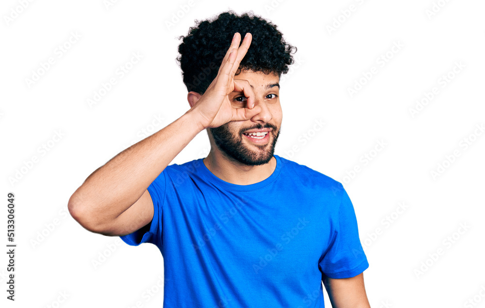 Young arab man with beard wearing casual blue t shirt doing ok gesture with hand smiling, eye looking through fingers with happy face. Young arab man with beard wearing casual blue t shirt doing ok gesture with hand smiling, eye looking through fingers with happy face.