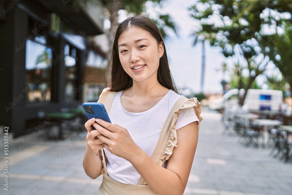 Young chinese girl smiling happy using smartphone at the city. Young chinese girl smiling happy using smartphone at the city.