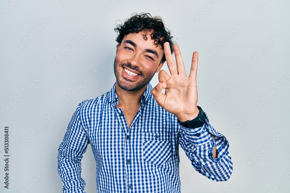 Fototapeta premium Young hispanic man wearing casual clothes showing and pointing up with fingers number three while smiling confident and happy.