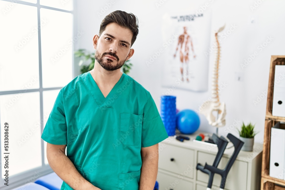 Young man with beard working at pain recovery clinic relaxed with serious expression on face. simple and natural looking at the camera. Young man with beard working at pain recovery clinic relaxed with serious expression on face. simple and natural looking at the camera.