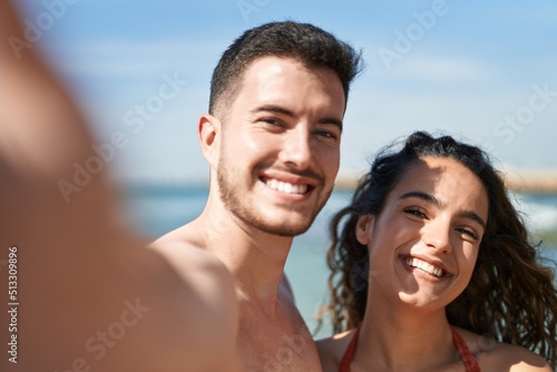 Young hispanic couple tourists wearing swimsuit make selfie by camera at seaside © Krakenimages.com