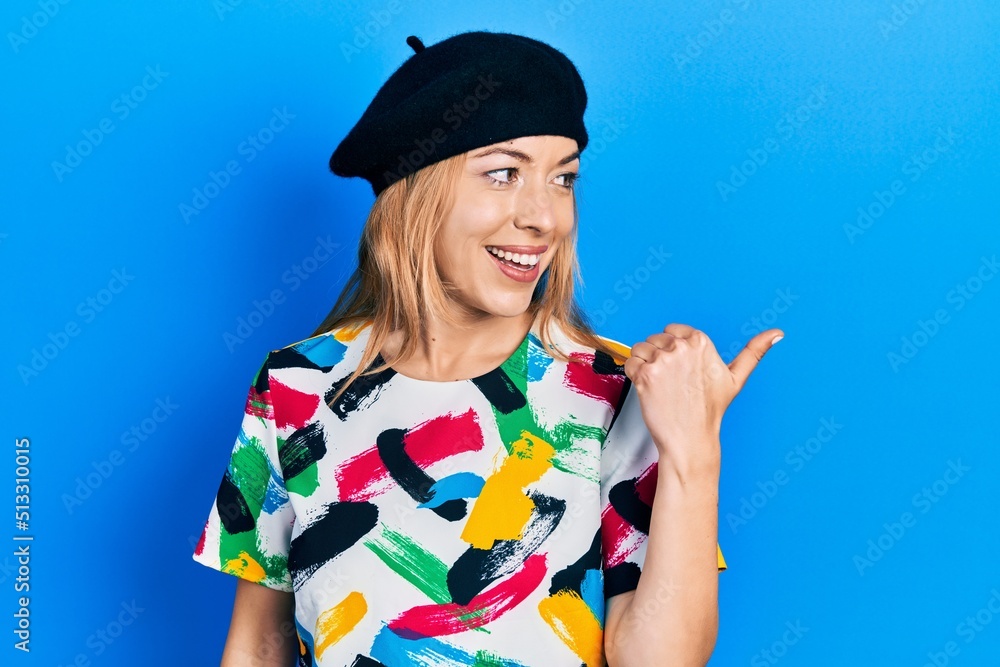 Young caucasian woman wearing french look with beret pointing thumb up to the side smiling happy with open mouth Young caucasian woman wearing french look with beret pointing thumb up to the side smiling happy with open mouth