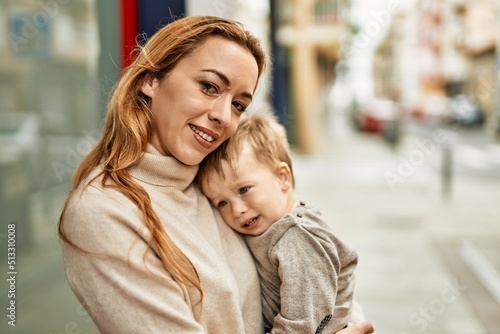 Beautiful family of mother and baby son hugging and bonding together with love. Parent and toddler outdoors