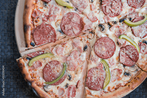 Delicious pizza with olives and pepperoni and peppers on a dark table, top view