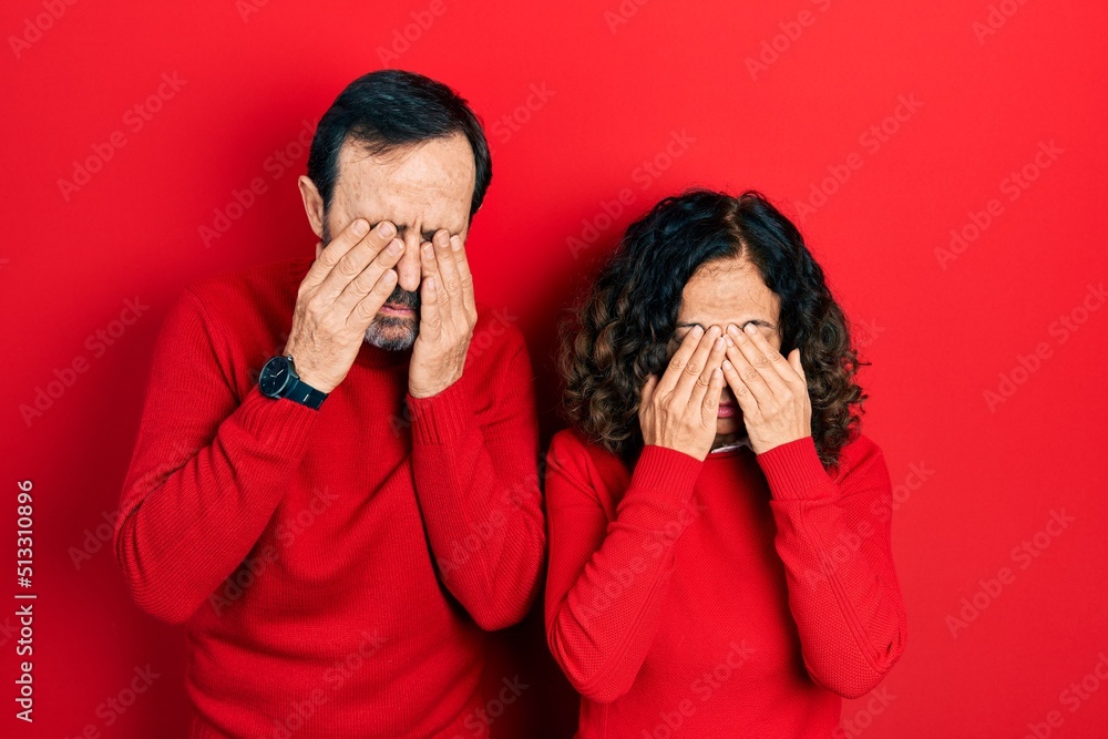 Middle age couple of hispanic woman and man hugging and standing together rubbing eyes for fatigue and headache, sleepy and tired expression. vision problem Middle age couple of hispanic woman and man hugging and standing together rubbing eyes for fatigue and headache, sleepy and tired expression. vision problem