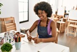 Young african american woman smiling confident manipulating clay at art studio