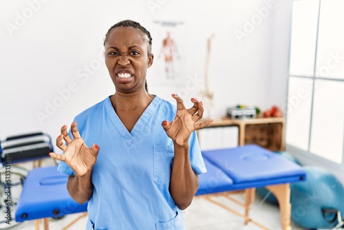 Black woman with braids working at pain recovery clinic disgusted expression, displeased and fearful doing disgust face because aversion reaction.