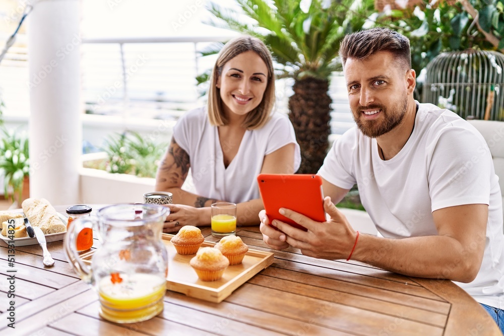 Young couple having breakfast using touchpad at terrace. Young couple having breakfast using touchpad at terrace.