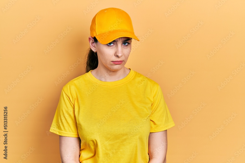 Young hispanic woman wearing delivery uniform and cap skeptic and nervous, frowning upset because of problem. negative person.